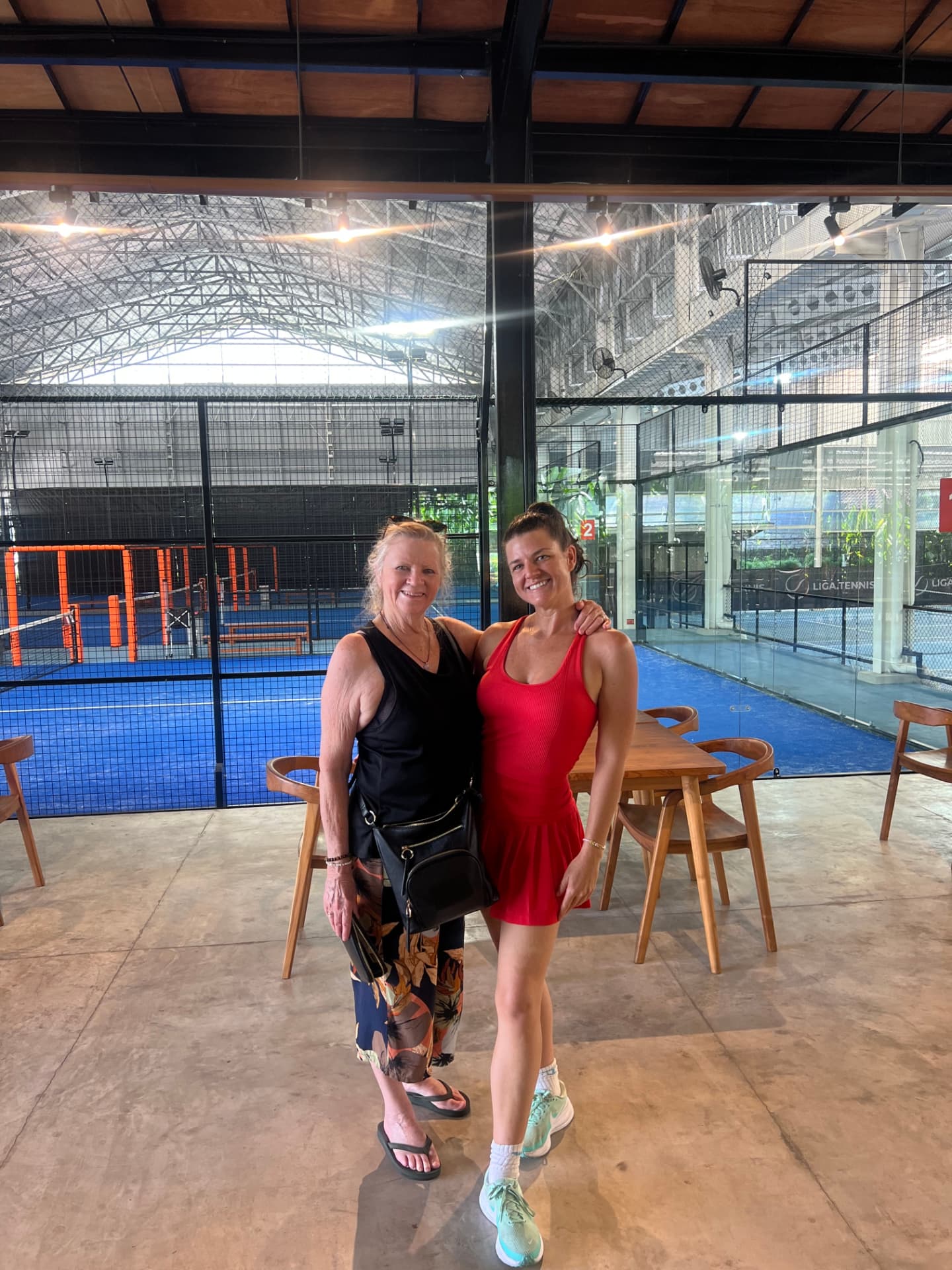 Two women smiling together at a covered court pavilion